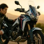 朝焼けの山岳ロードで日本人ライダーがアフリカツイン1100に荷物を積み、ツーリングの準備をする情景（16:9）— 自由と冒険を感じさせる中古バイク購入ガイド用アイキャッチ画像